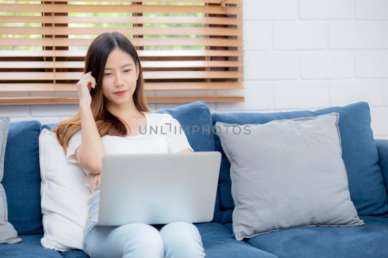 Young asian woman work on laptop computer on sofa at home with frustrated and bored, freelance girl unhappy and tired with unsuccessful, upset from problem, failure and mistake, business concept.