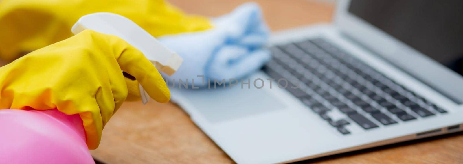 Hand of young asian woman cleaning and wipe laptop computer with disinfect and alcohol for protect pandemic covid-19 at home, girl in gloves cleaner notebook for hygiene, banner website.