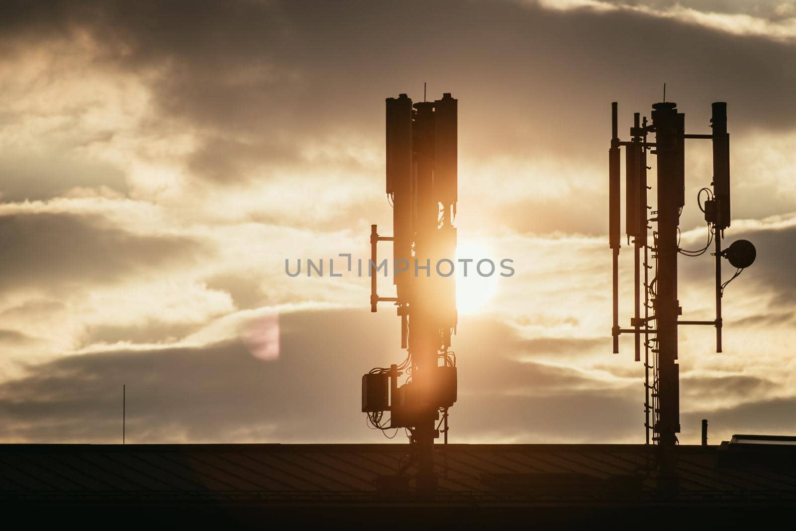 Silhouette of communication or cell tower on the rooftop of a building, evening sunshine