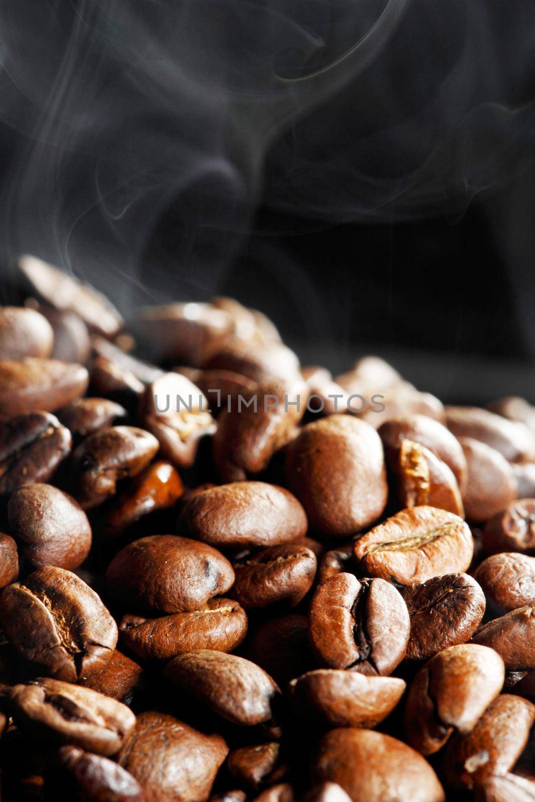 Hot roasted coffee beans and steam on black background with copy space