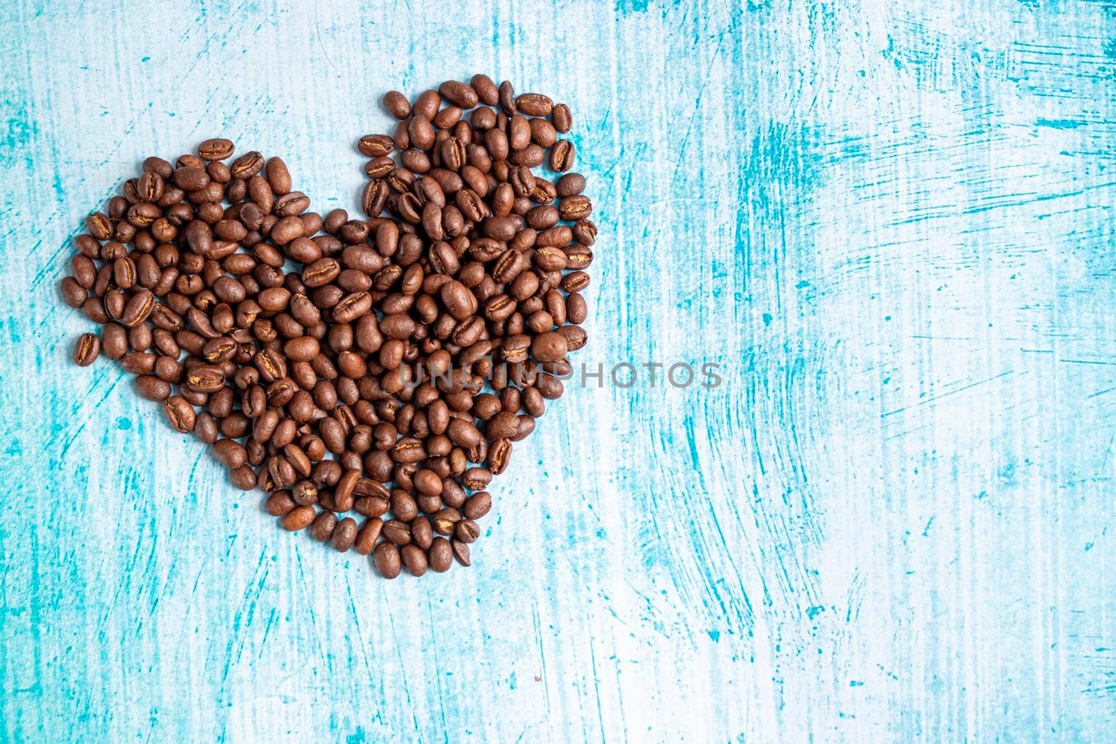 Heart shaped coffee grains on aquamarine background