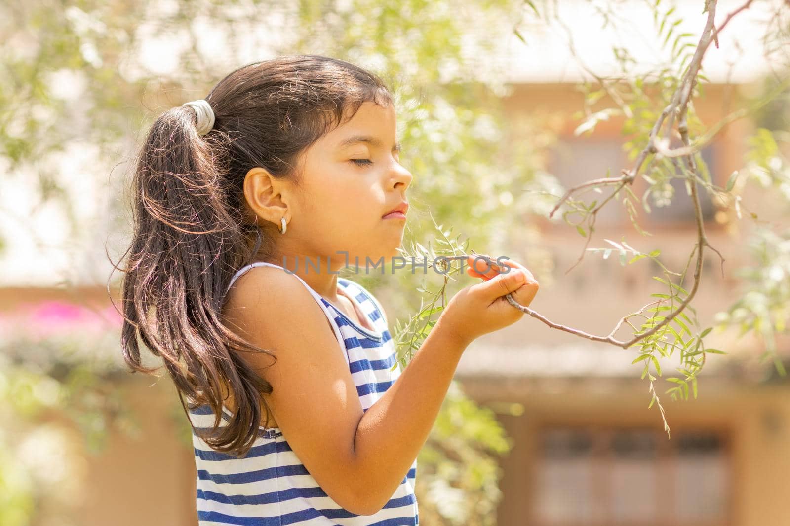 Little girl enjoying the smell of plants in nature