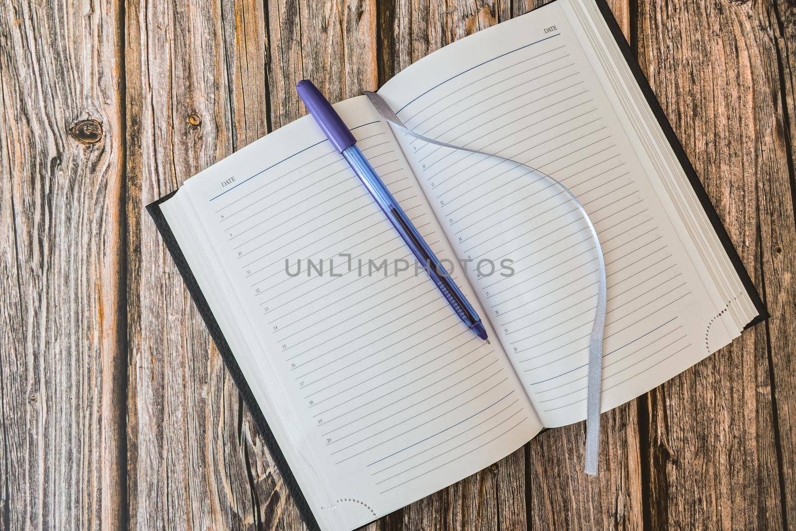 Opened diary or notebook for notes with pen on wooden table top view