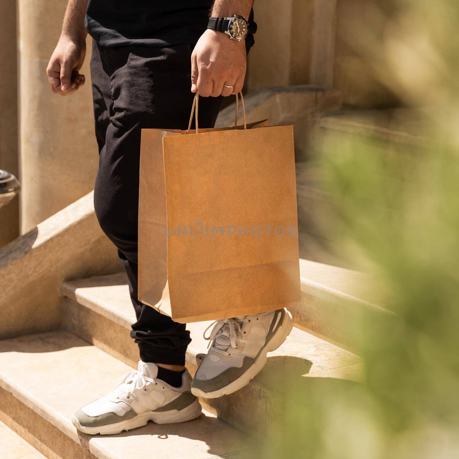 Man going down the stairs with shopping bag by ferhad