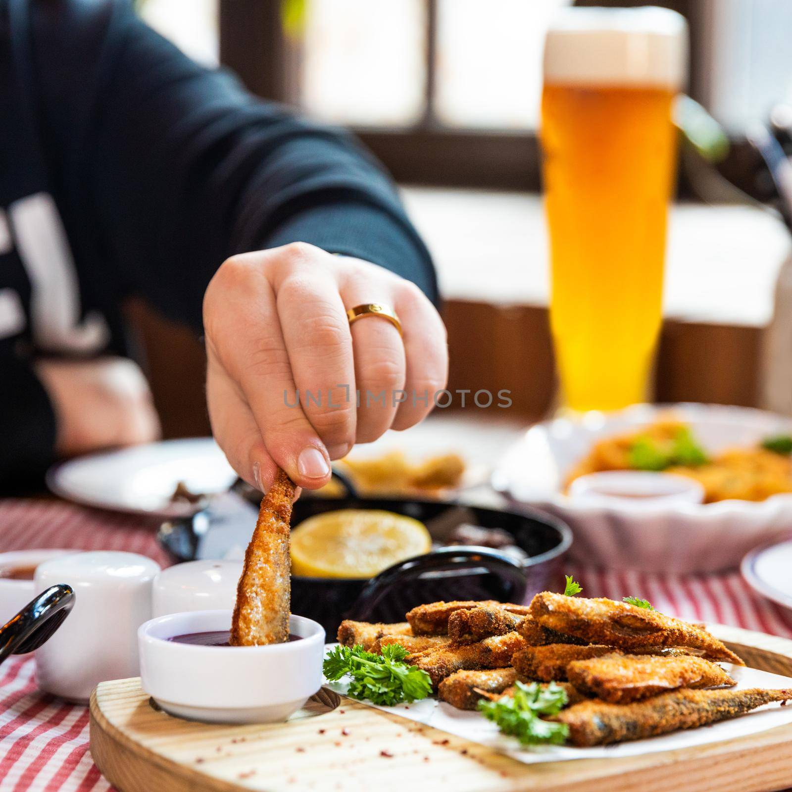 Man dipping Kilka, Sprat fish to the ketchup close up by ferhad