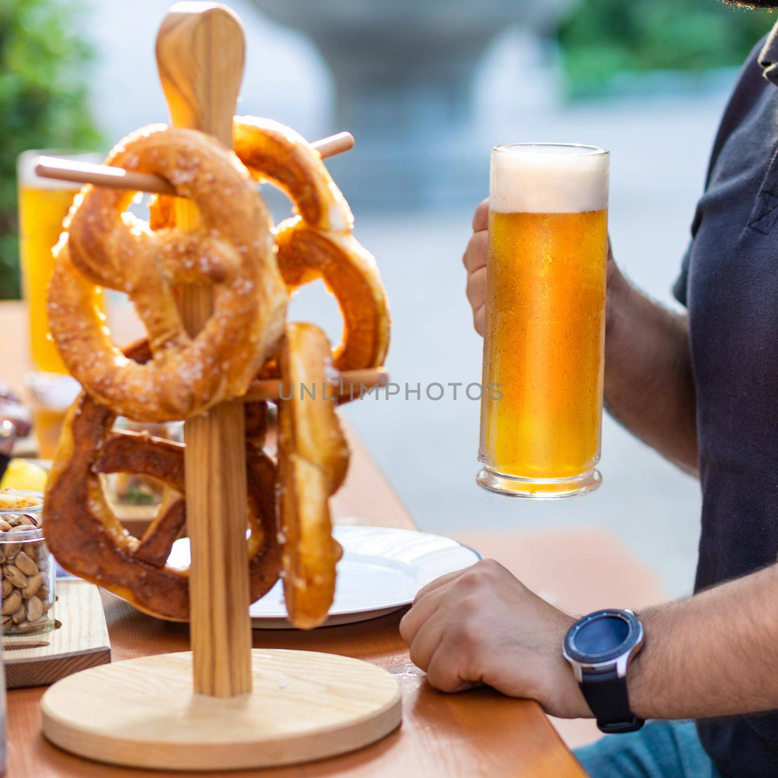 Man holding beer mug with pretzel on the table