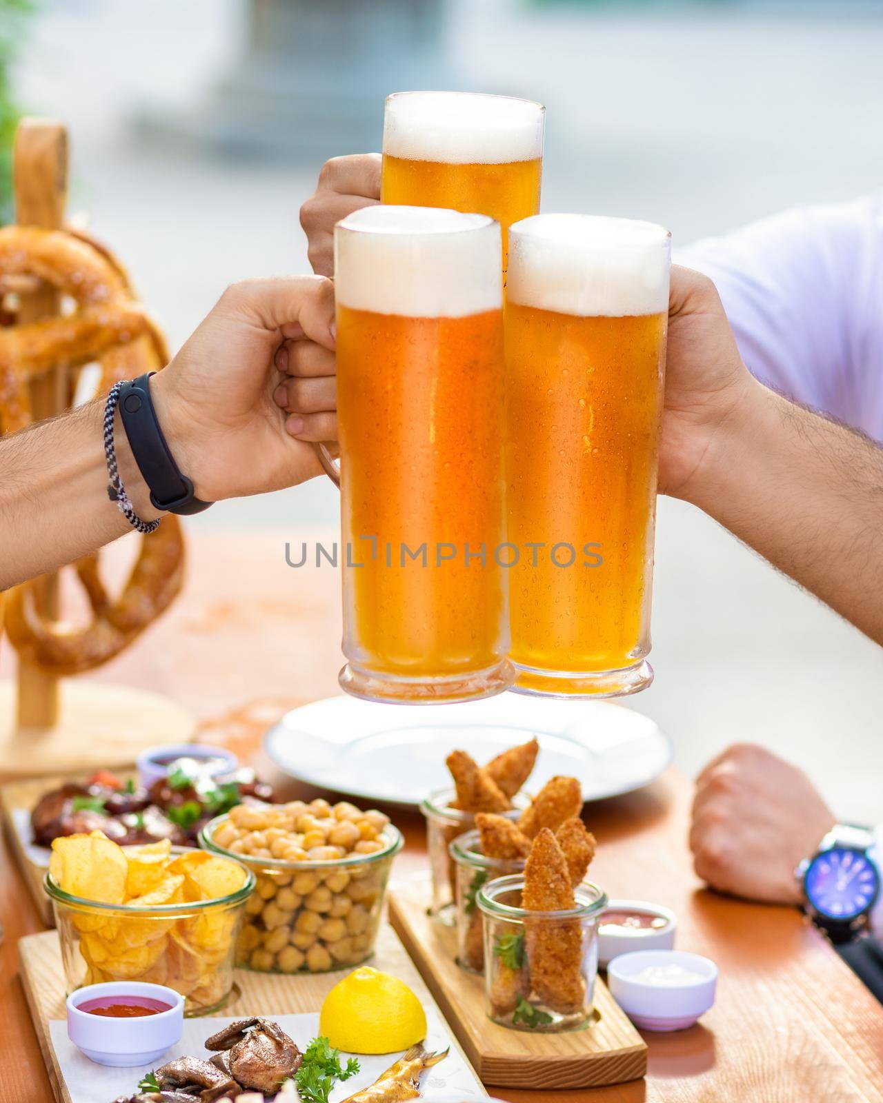 Clinking beer mugs outside, snacks on the table by ferhad
