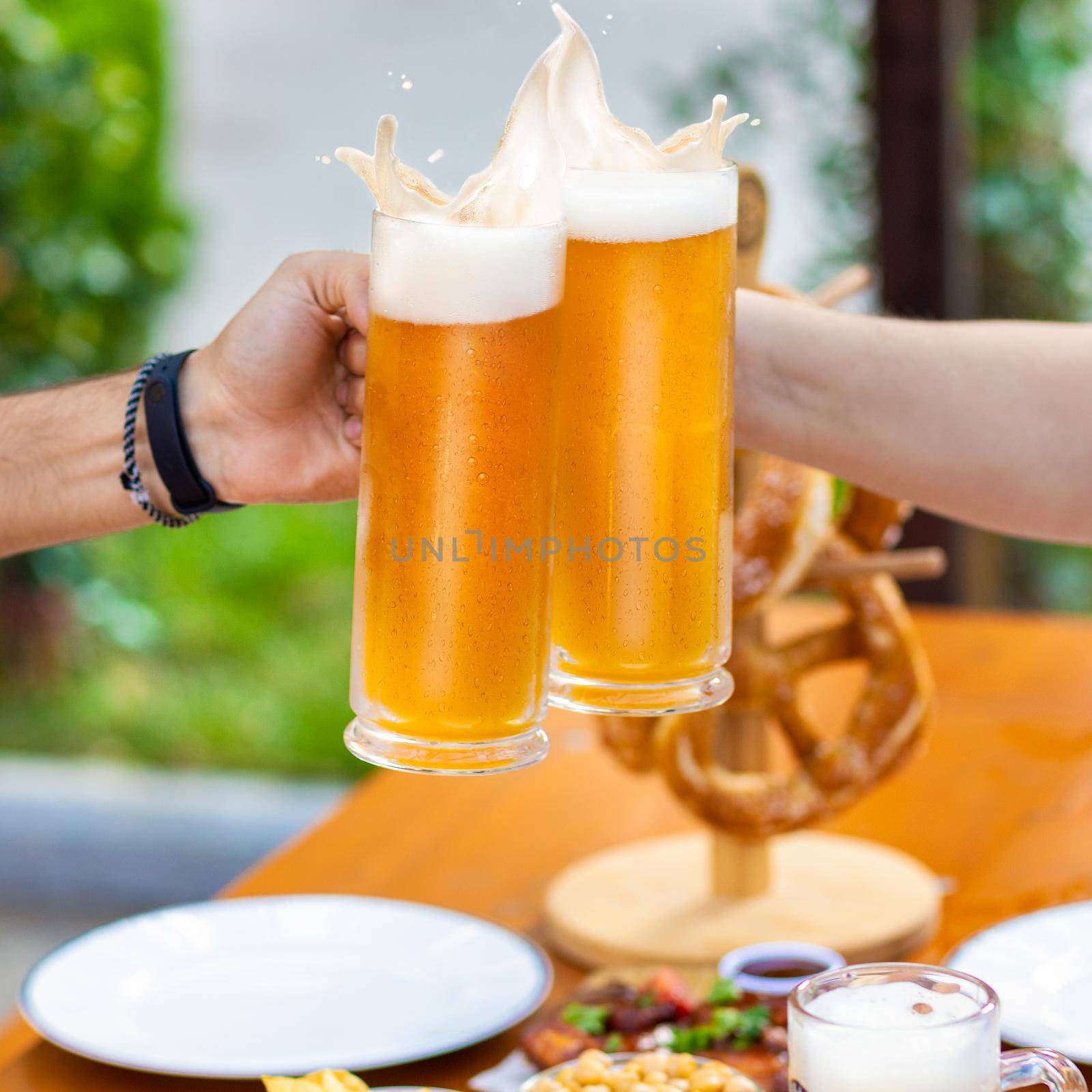 Clinking beer mugs outside, snacks on the table