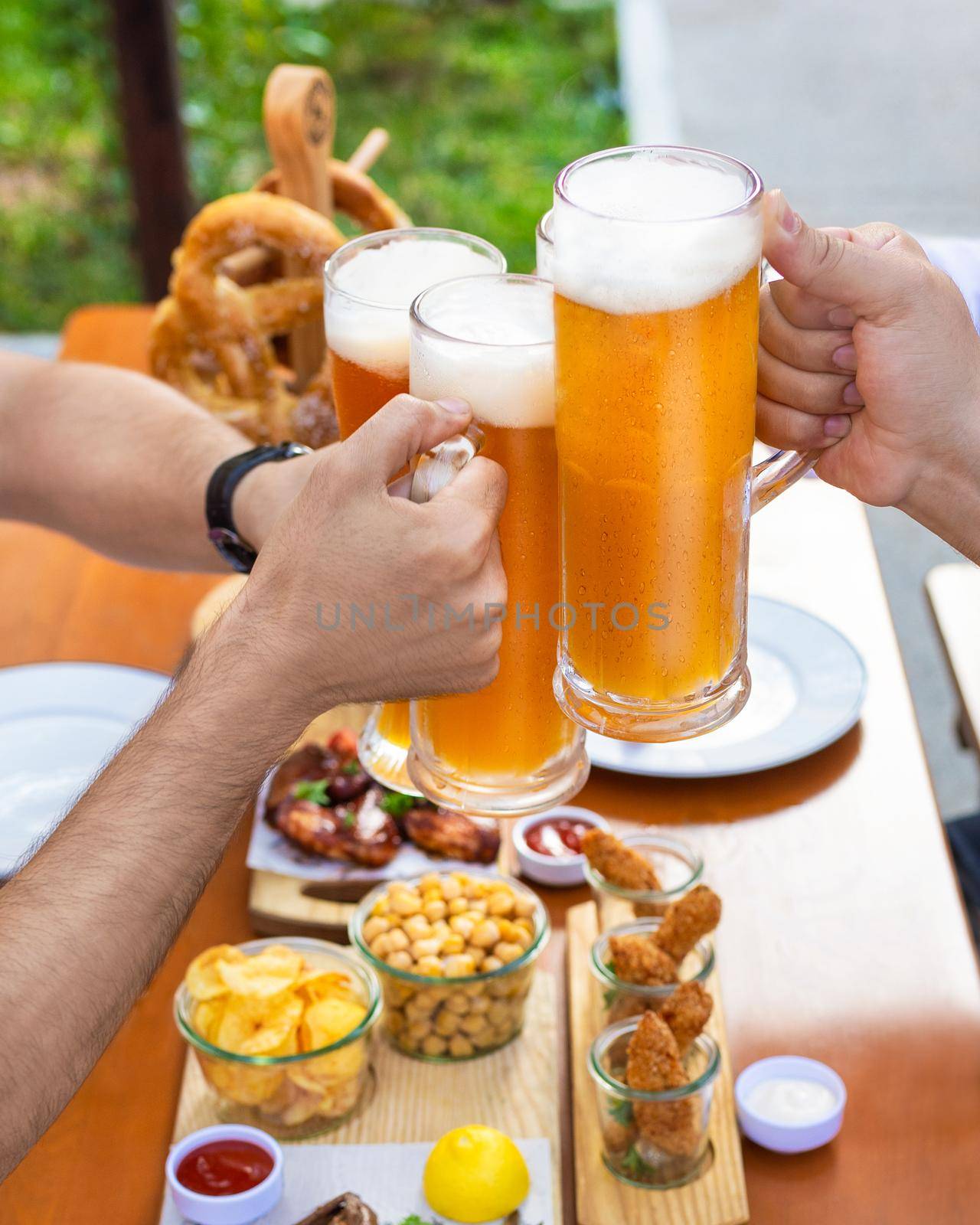 Clinking beer mugs outside, snacks on the table