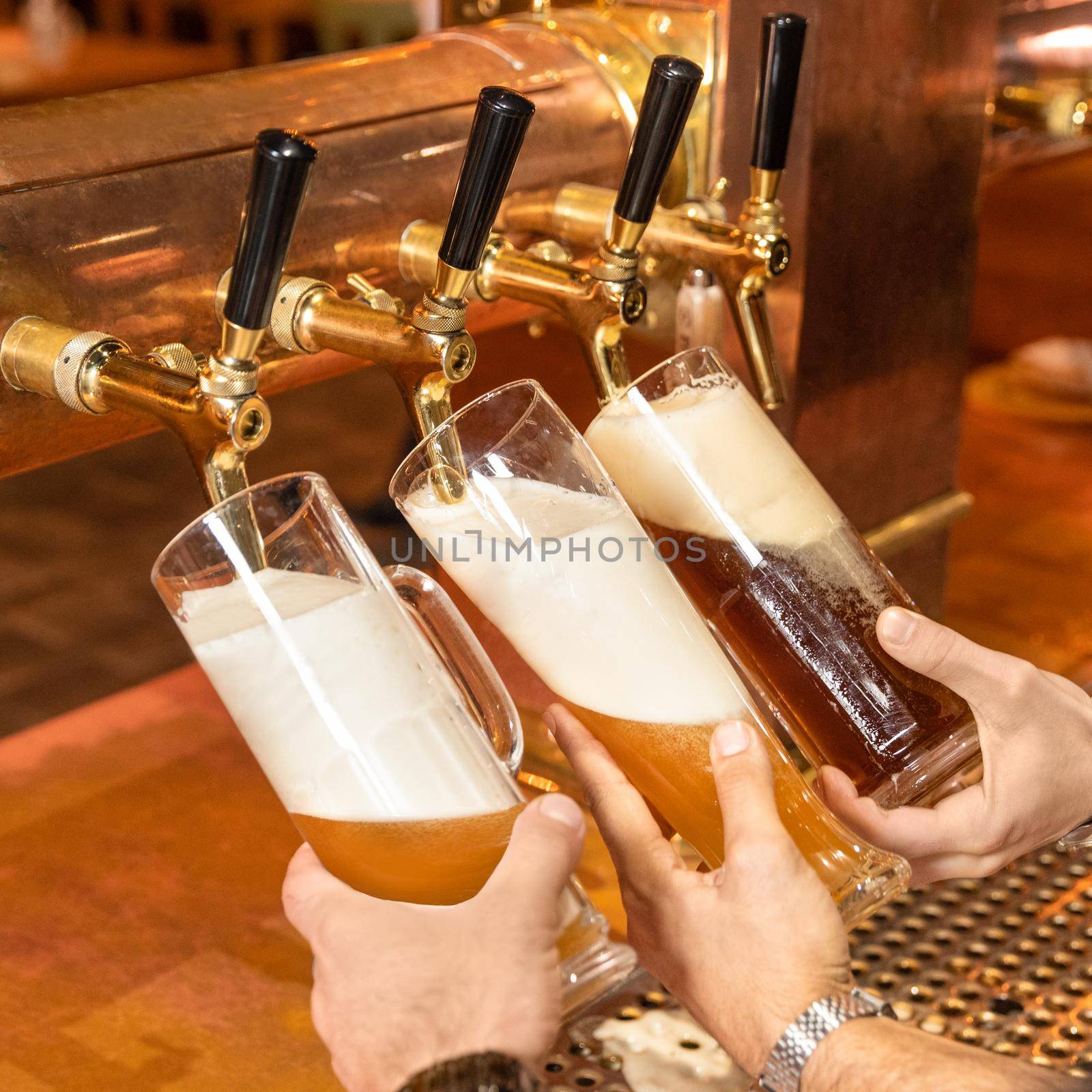 Pouring, filling beer glasses, mugs from barrel