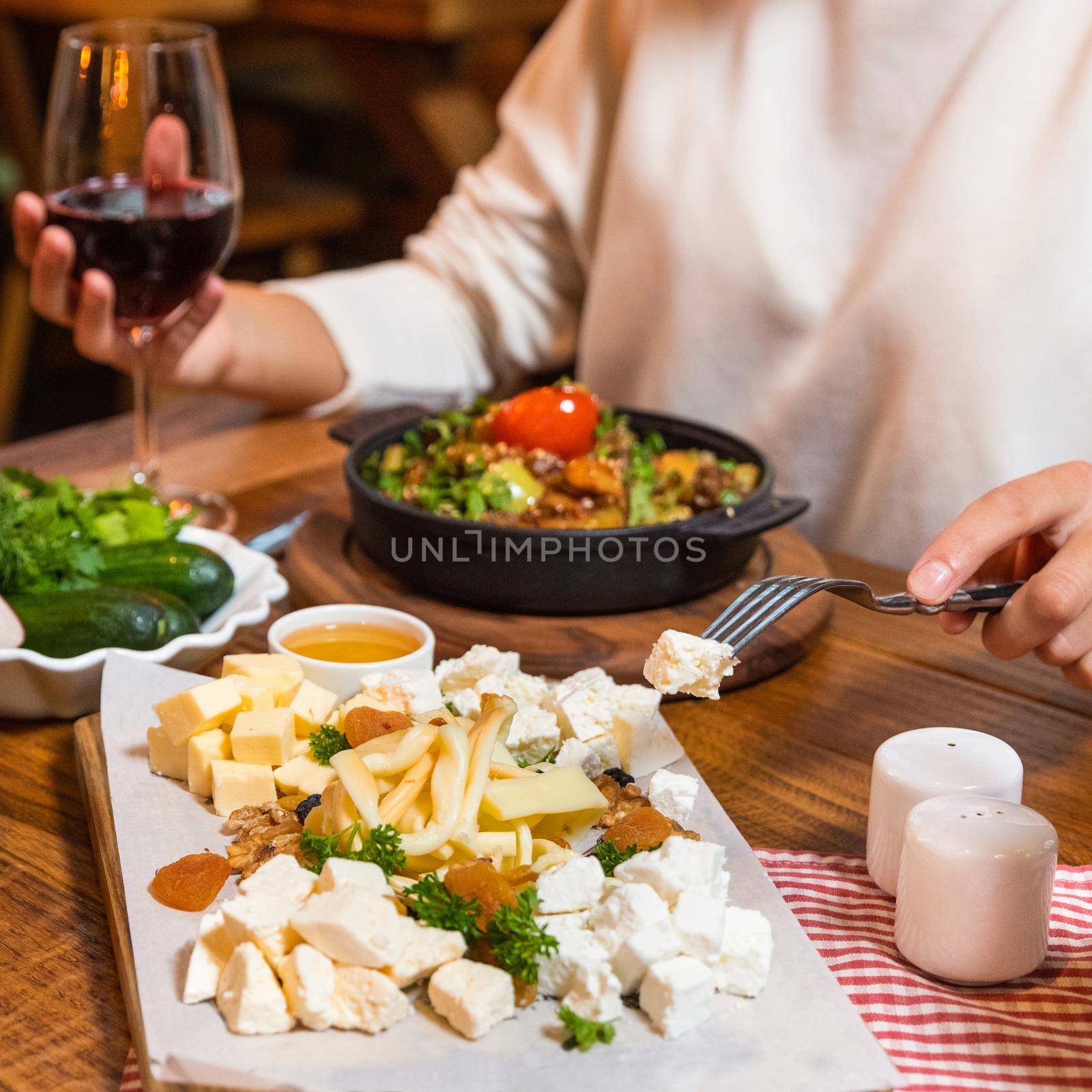 Woman eating tasty meat meal on the wooden plate with red wine by ferhad