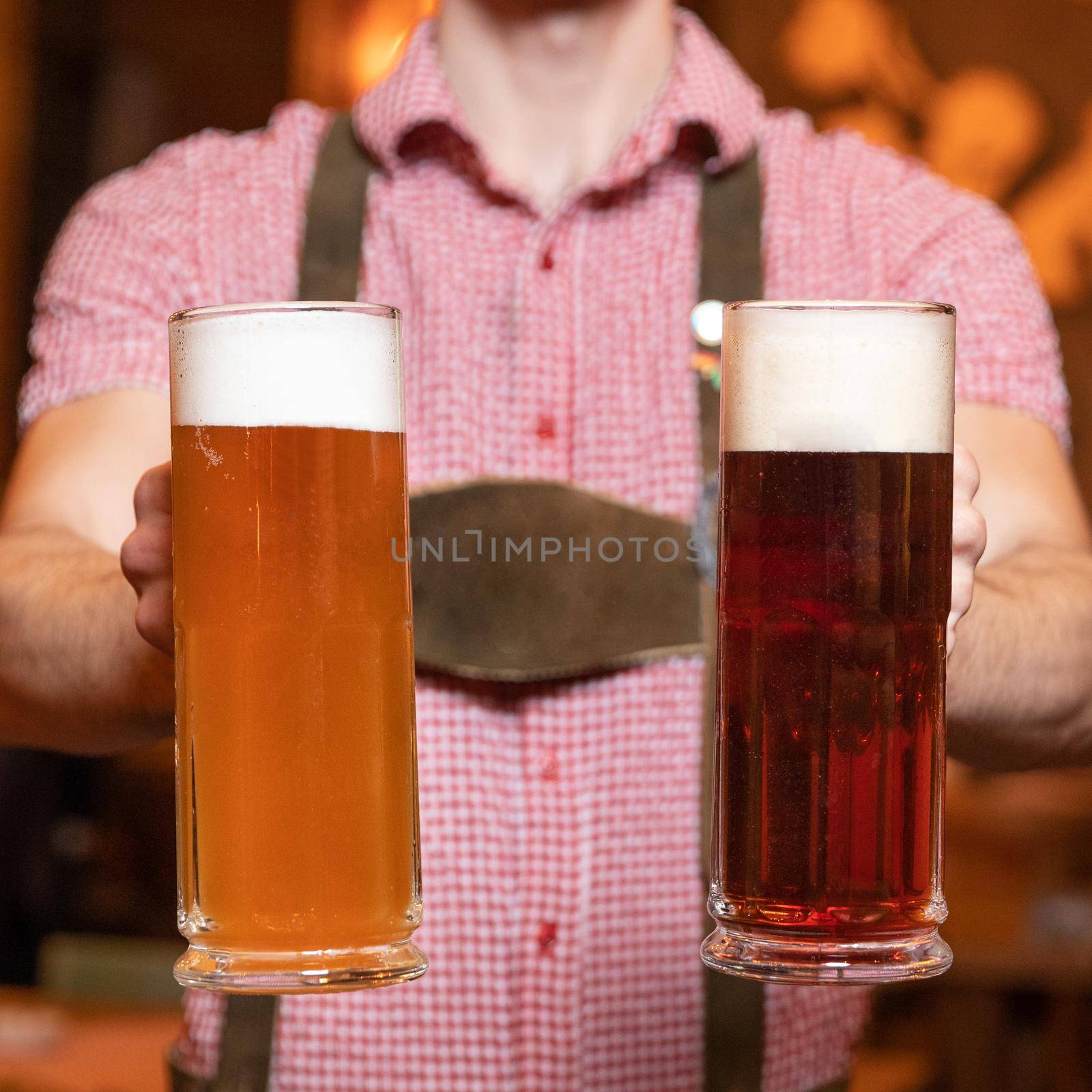 Man holding white and black, dark beer glasses side by side