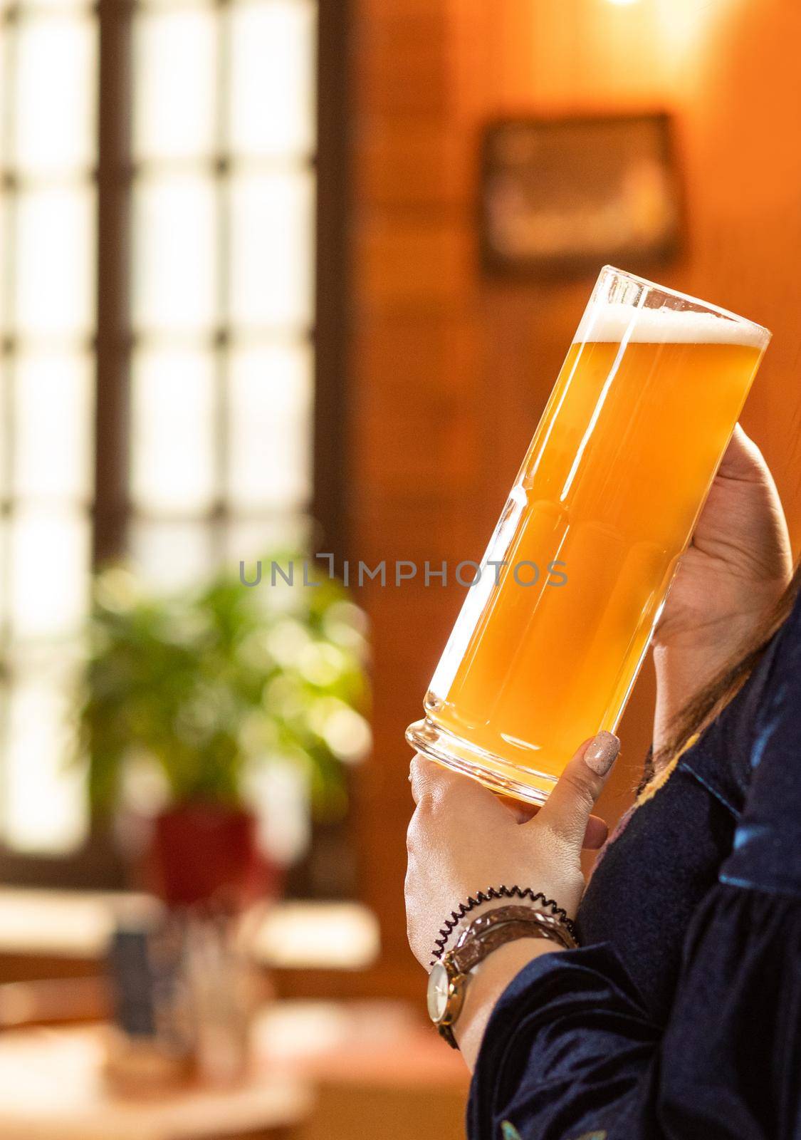 Woman drinking beer, holding mug at the restaurant