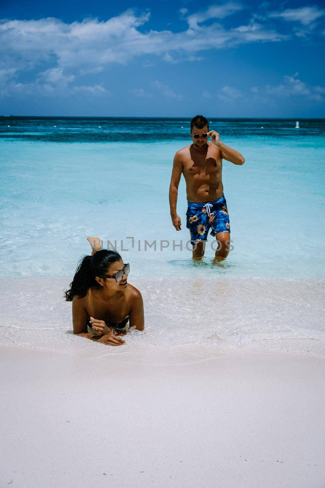 Palm Beach Aruba Caribbean, white long sandy beach with palm trees at Aruba Antilles, couple man and woman mid age on a white beach with palm trees