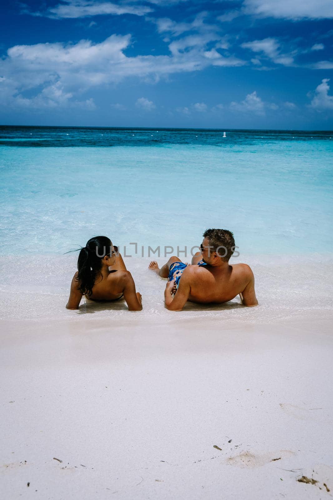 Palm Beach Aruba Caribbean, white long sandy beach with palm trees at Aruba Antilles, couple man and woman mid age on a white beach with palm trees