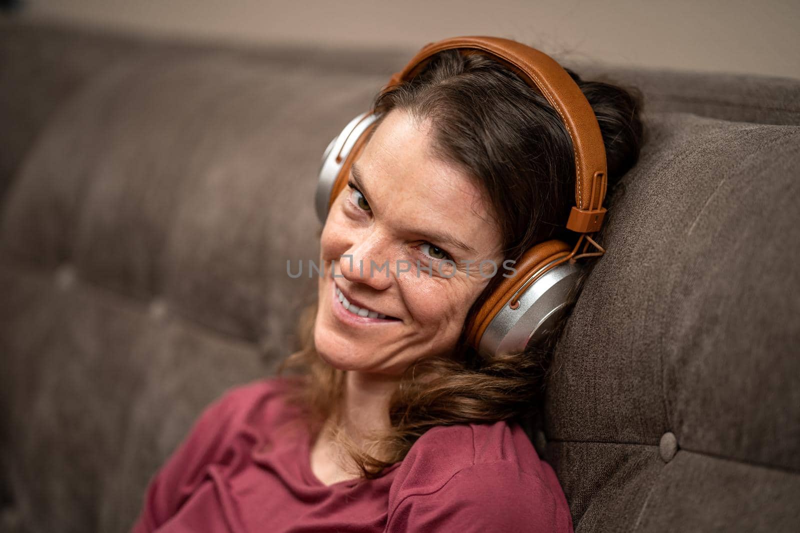 young woman with wireless headphones on her head on the couch by Edophoto