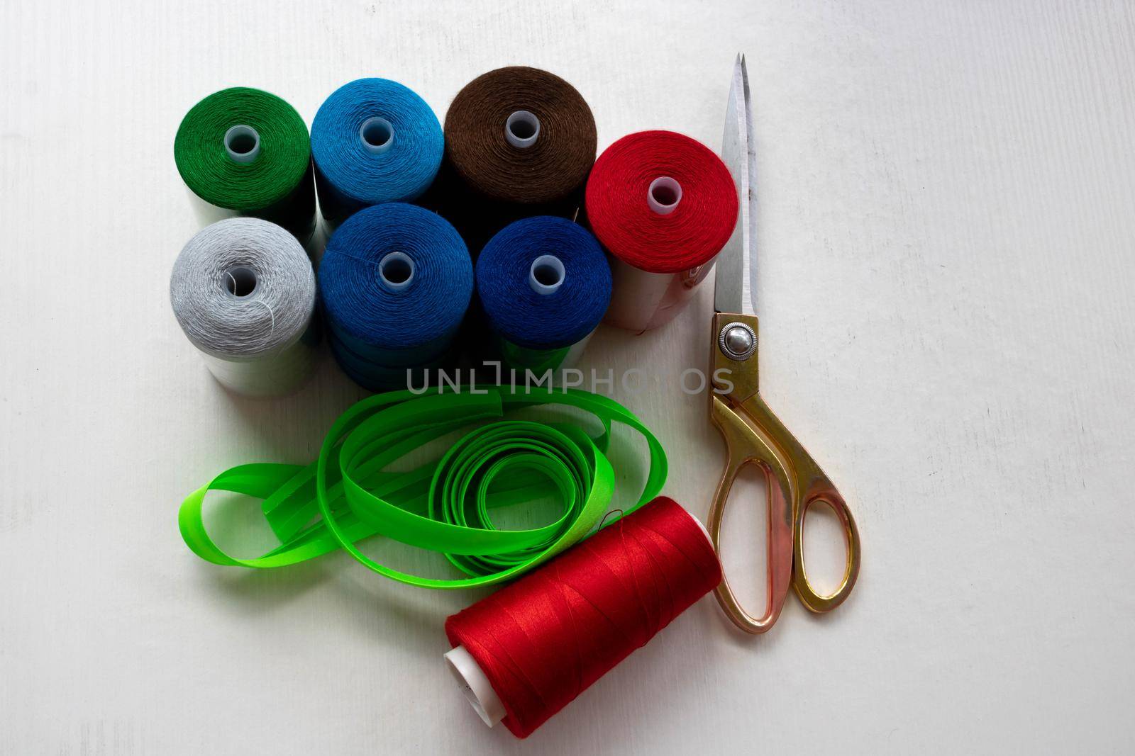 Colorful threads and scissors on a white background.