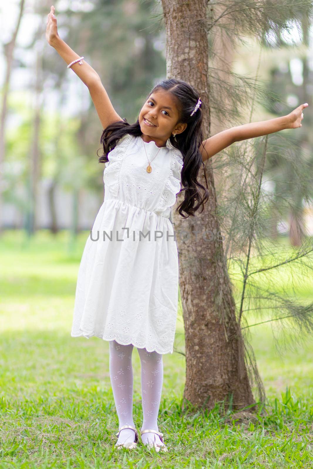 Little girl with white dress and red sweater, very happy and smiling in the forest