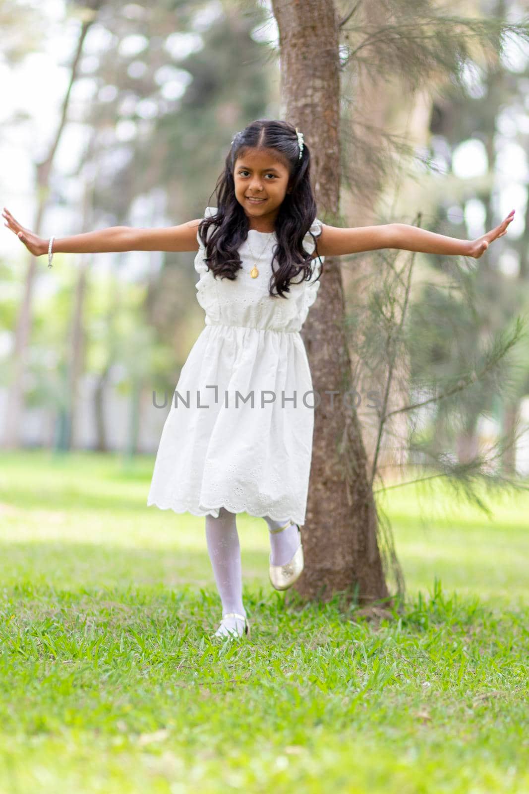 Little girl with white dress and red sweater, very happy and smiling in the forest