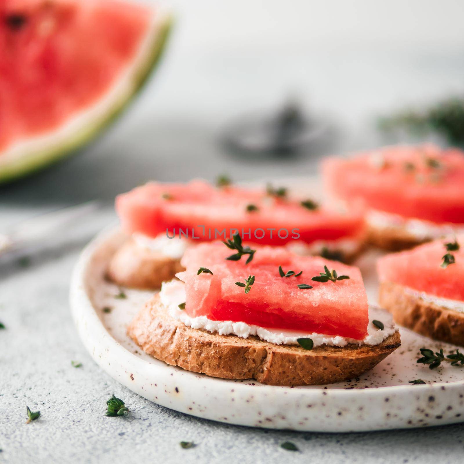 Toasts with soft cheese, watermelon and fresh thyme.Salty cheese,sweet watermelon and spicy thyme on crispy grilled bread slices. Idea and recipe for unusual healthy breakfast, summer snack or lunch
