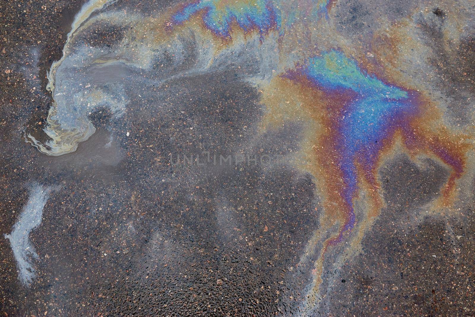 Colored oil stains in the car park, the color of the gasoline stain on the pavement road as a background.Abstract rainbow effect background