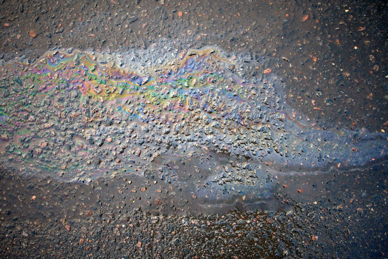 Gasoline flows on the asphalt surface. Iridescent stains of gasoline.