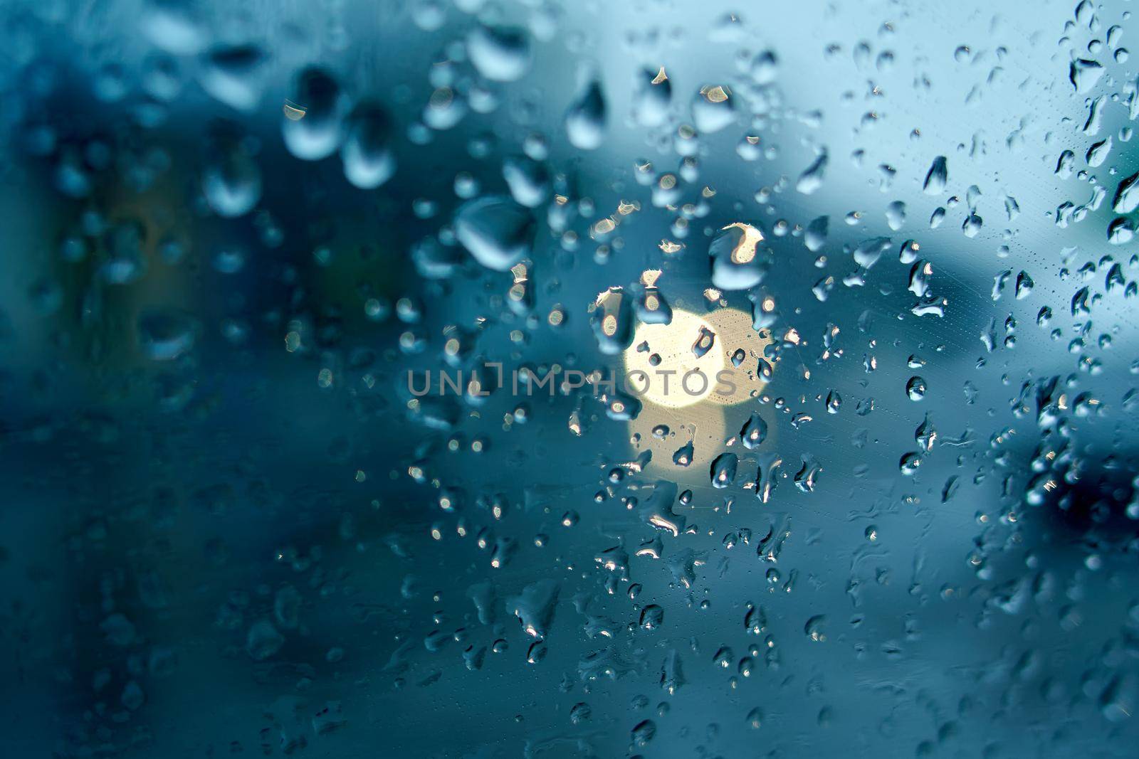 Water drops on the side window of the car. View from the inside of the car during the rain on the evening city street. Soft selective focus