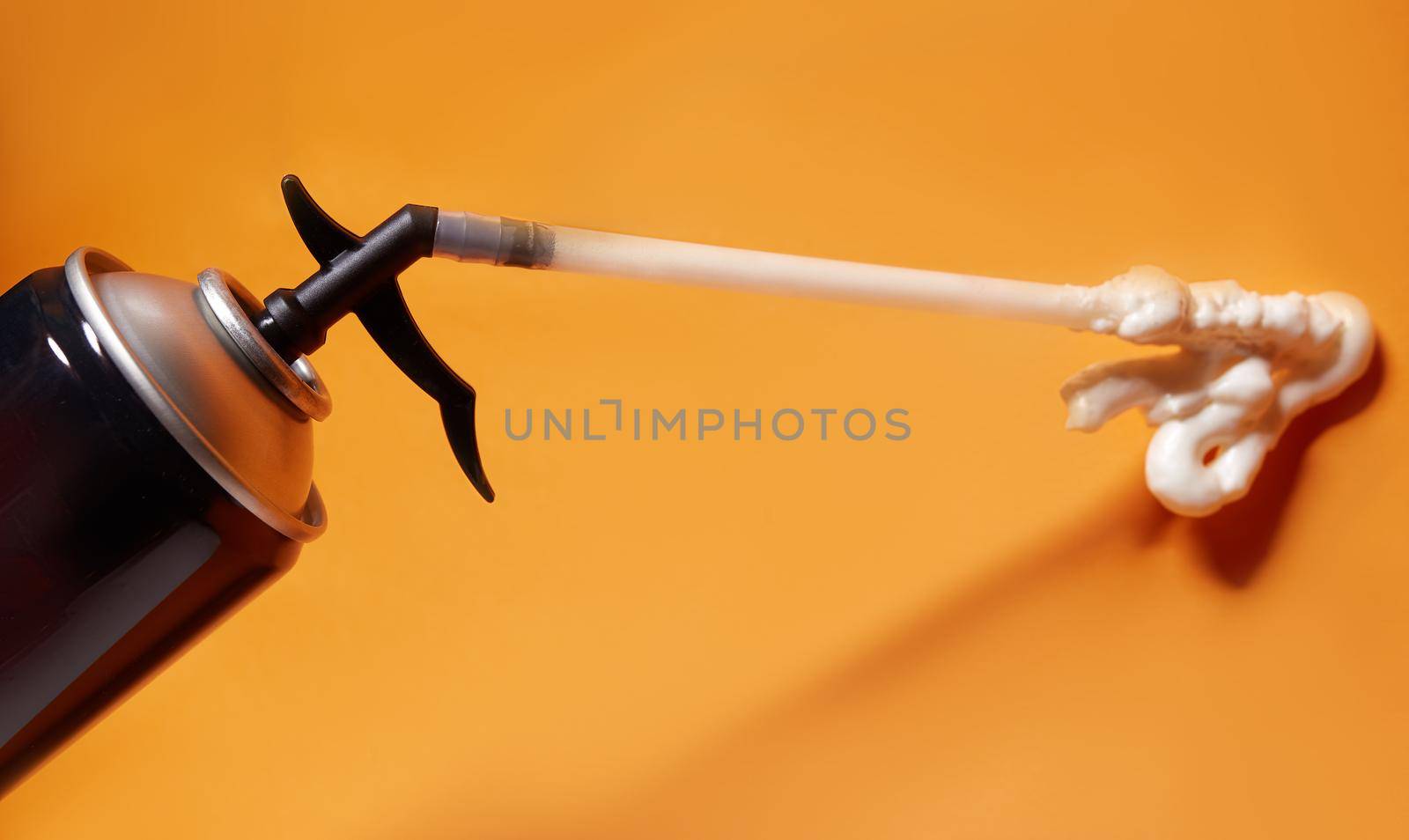Spray can of professional construction foam. Pu-foam, tube with building sealant for fixing or repair. Polyurethane Foam In Tube on orange background