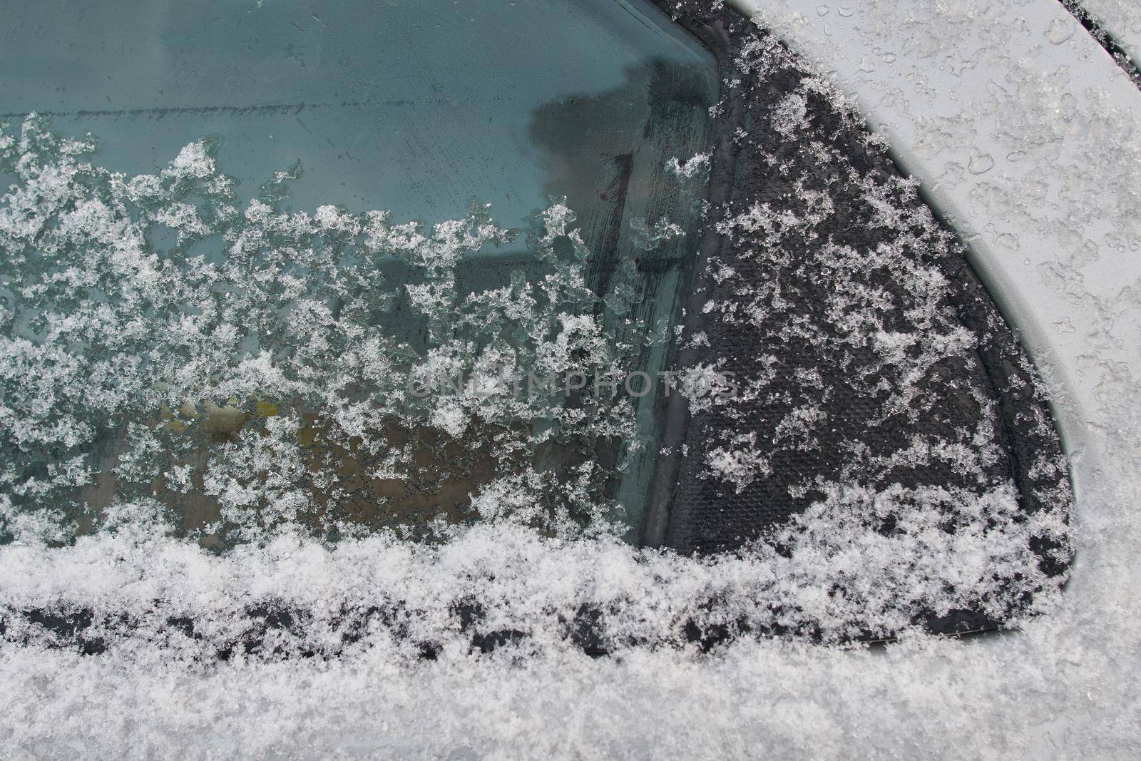 Snow-covered car window, natural background, first snow. Close-up