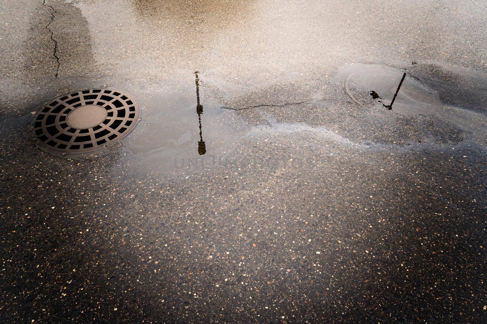 Oil slick on the asphalt road background drains into the storm drain.Water pollution environmental problems