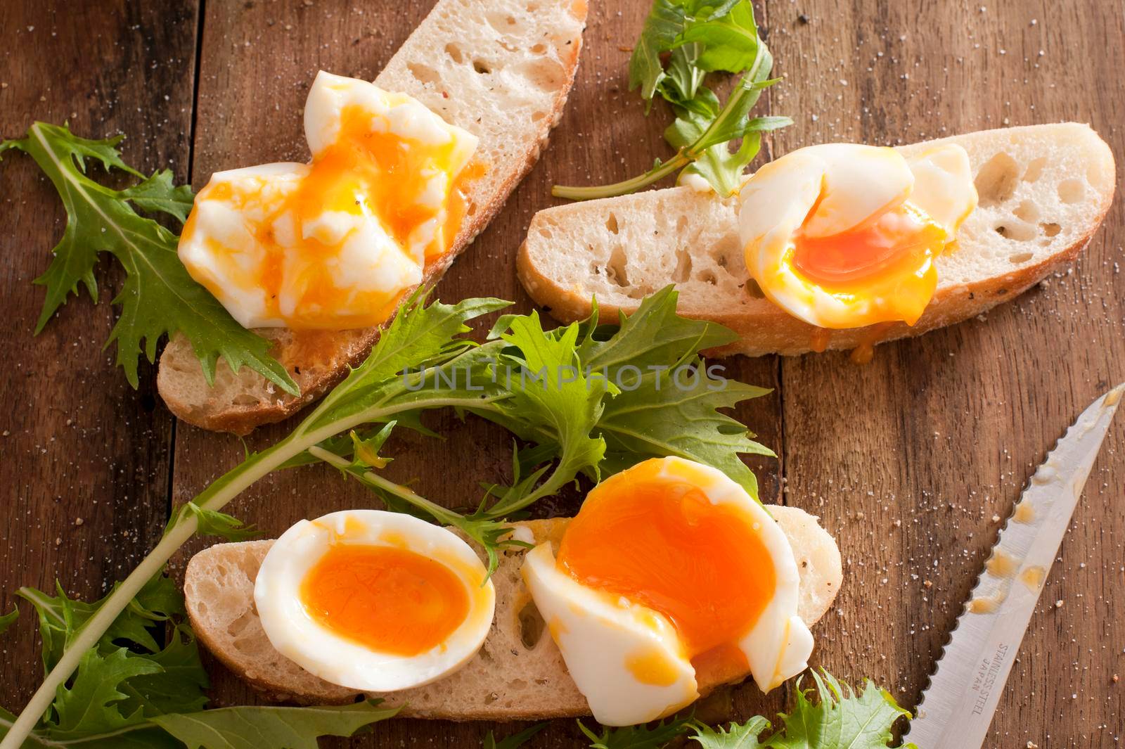 Soft boiled eggs broken open on baguettes by stockarch