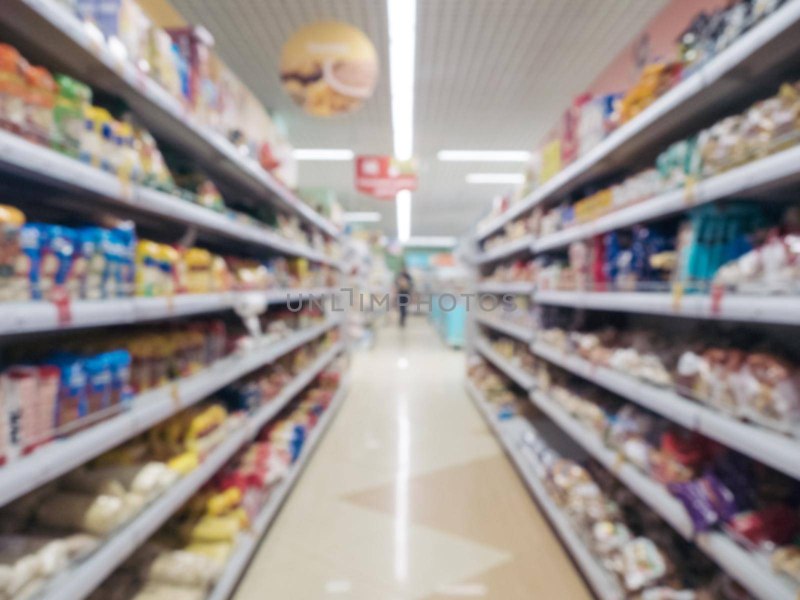 Abstract blurred supermarket aisle with colorful shelves and unrecognizable customers as background