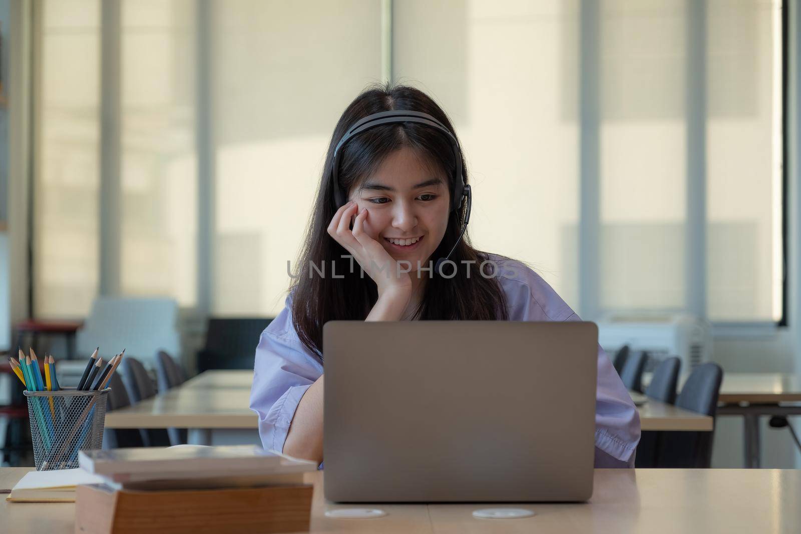 Portrait young asian girl looking camera while using laptop computer by nateemee