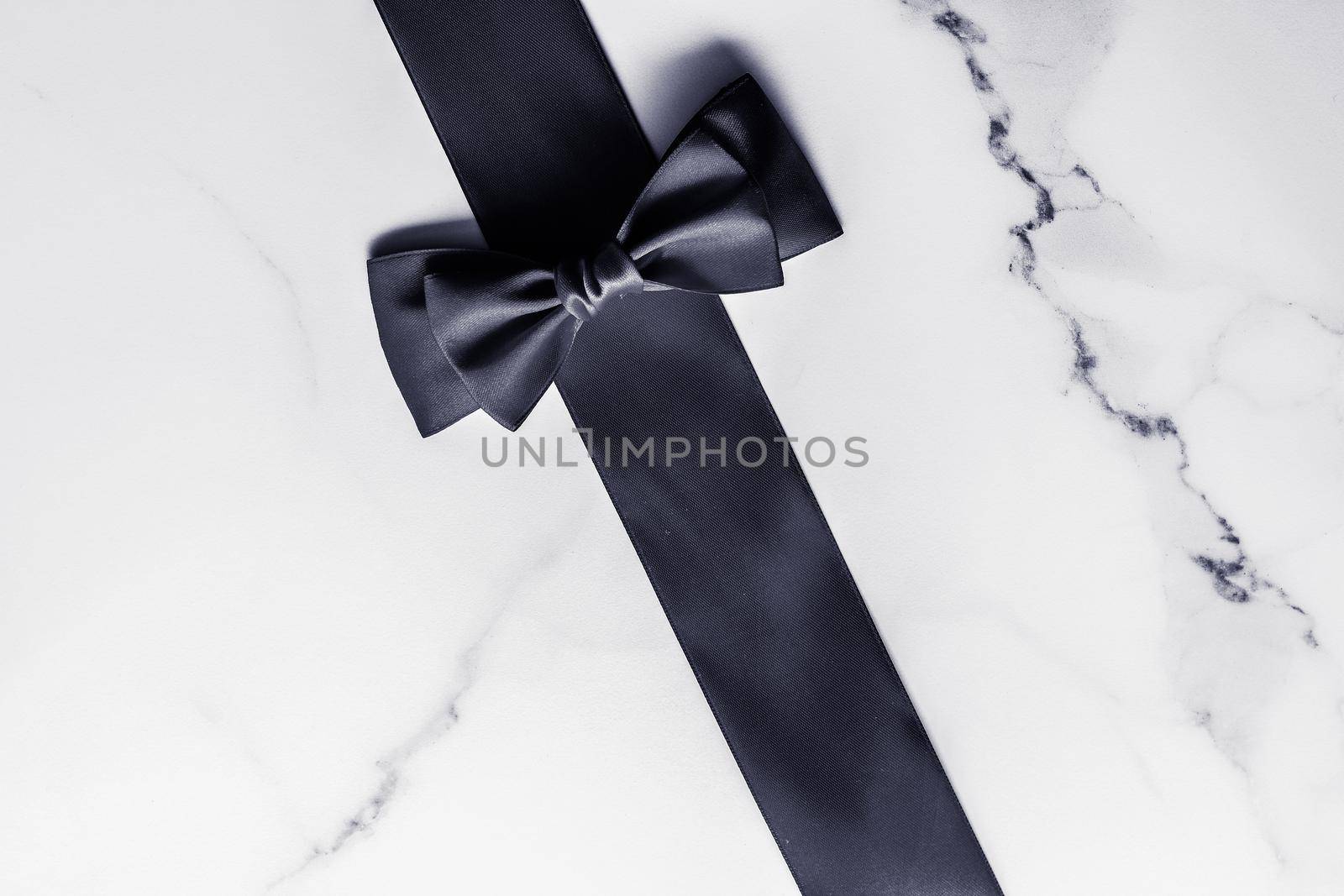 Holiday gift, decoration and sale promotion concept - Black silk ribbon and bow on marble background, flatlay