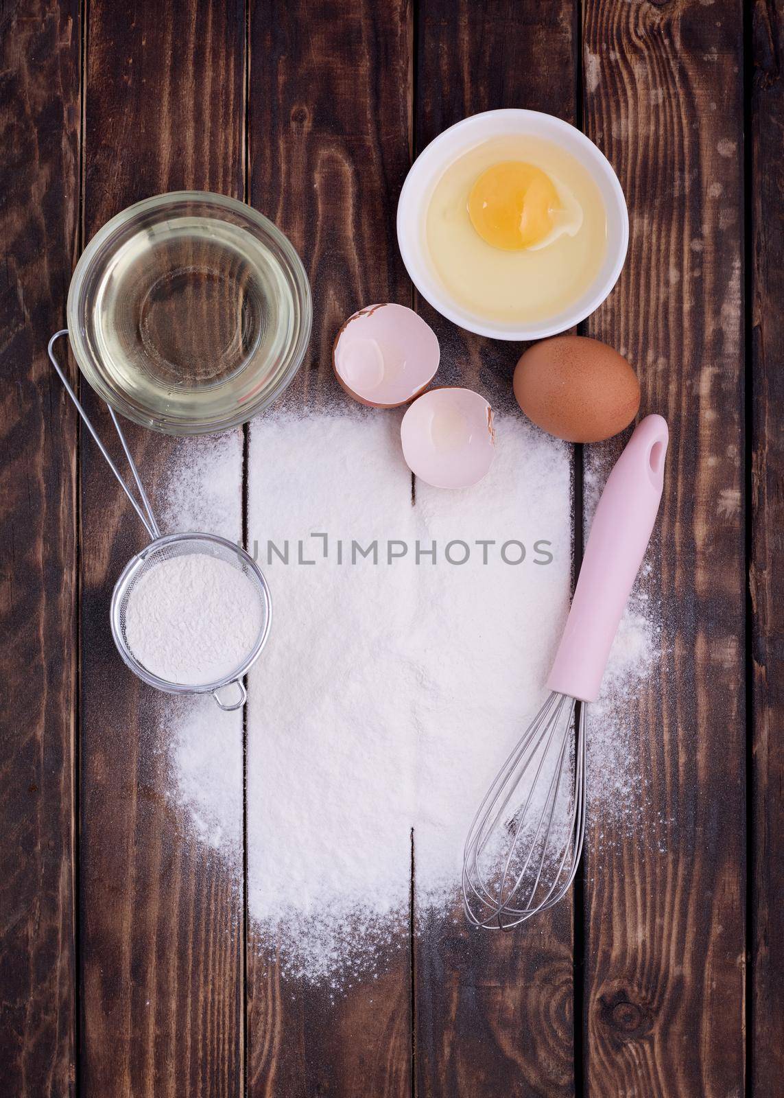 baking ingredients egg, flour, oil and muffin for baking on a wooden background