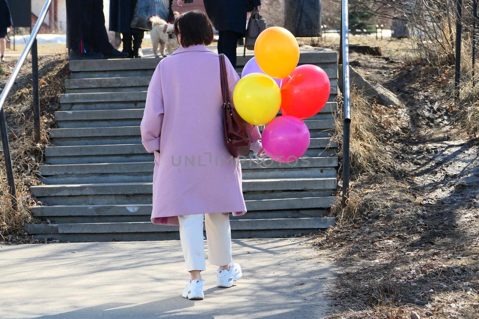 A girl in bright clothes on the street, a view from the back. It's a sunny day. High quality photo