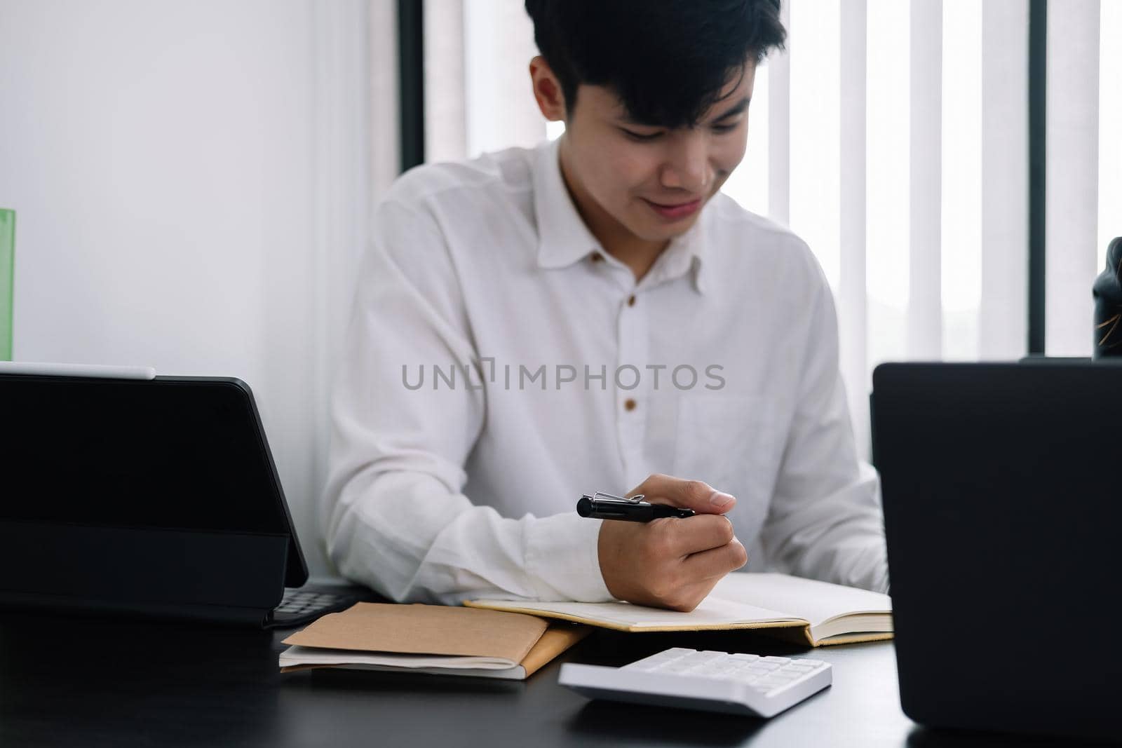 Businessman holding pen and taking note when meeting at office by nateemee