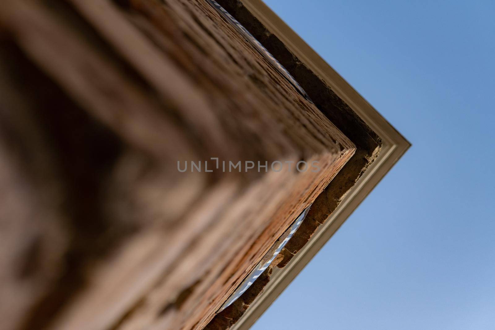 Corner of an old building seen up close and from below with a blue sky. by xavier_photo