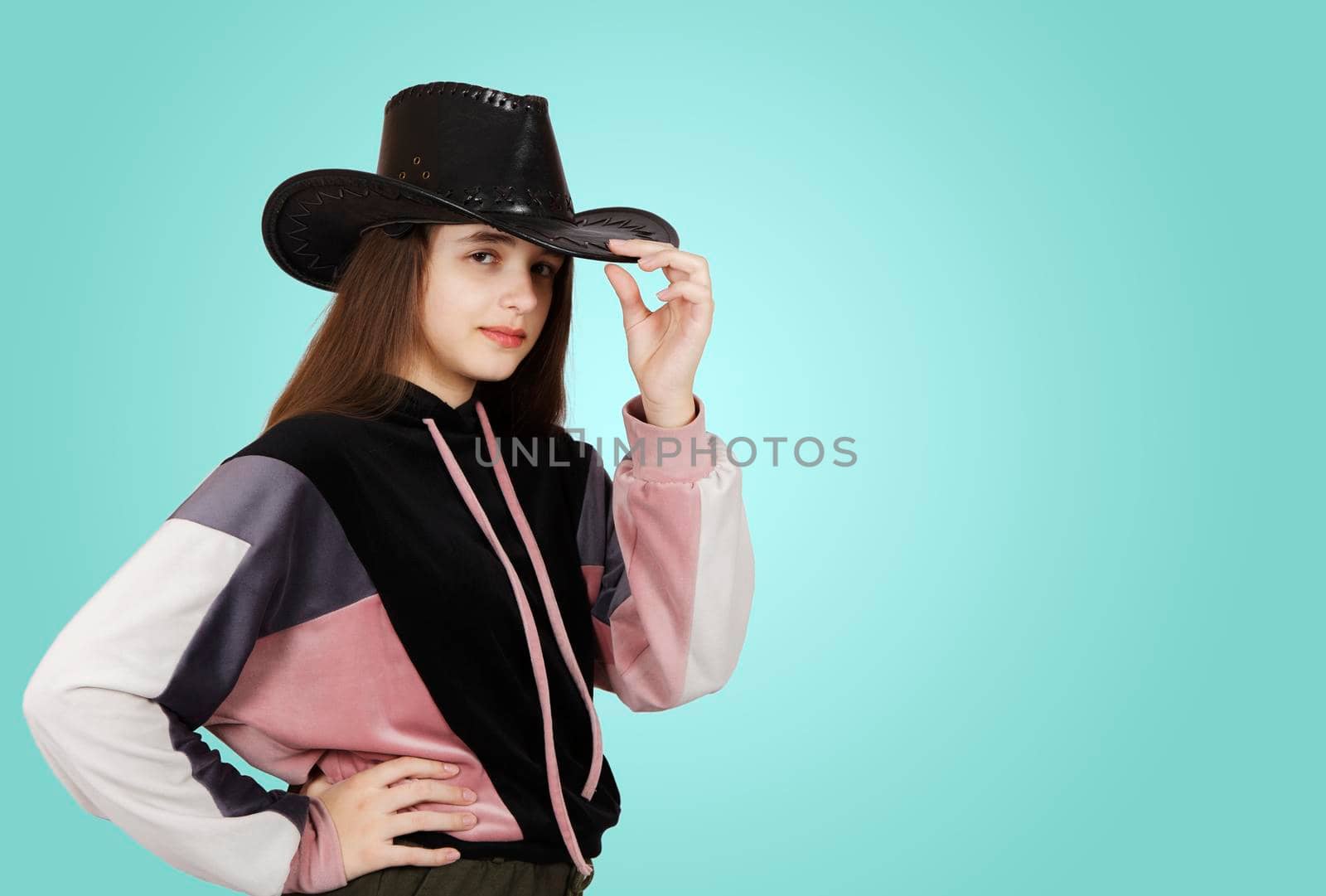 teenage brunette girl posing with black hat in studio on green background