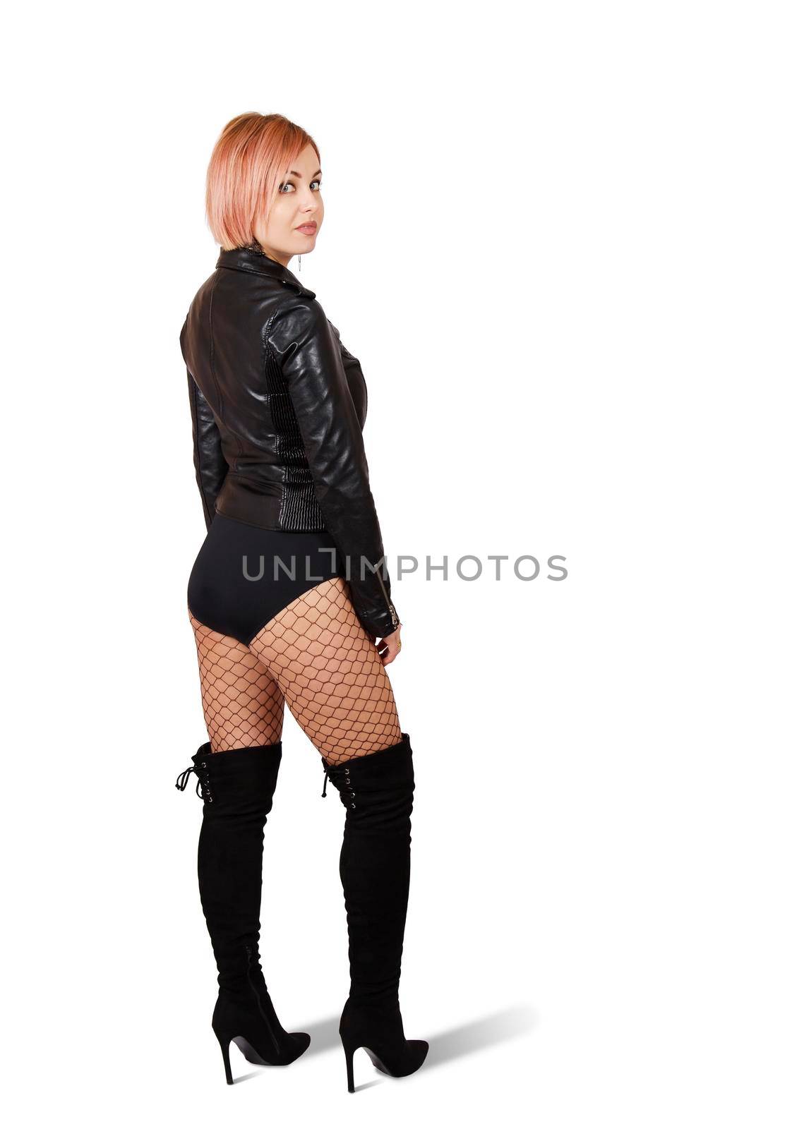 young woman in leather jacket, mesh tights and boots posing standing in studio on white background