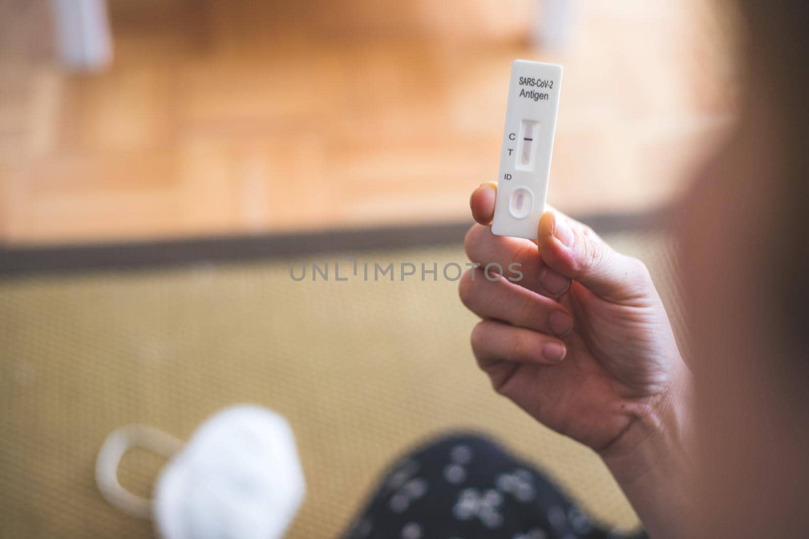 Close up of female fingers holding express antigen covid test, negative result, ffp2 mask in blurry background