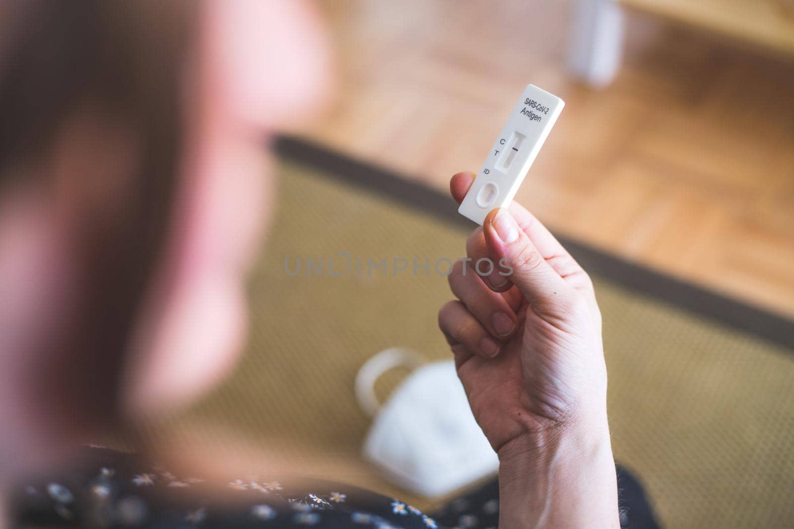 Close up of female fingers holding express antigen covid test, negative result, ffp2 mask in blurry background