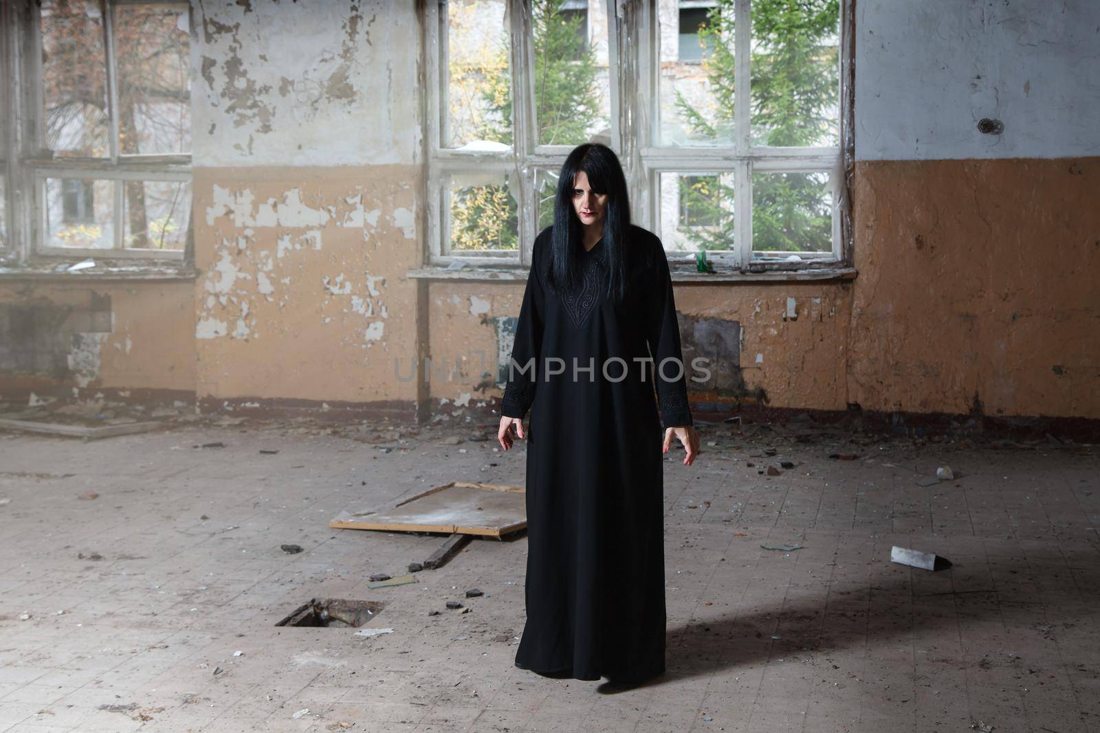 young goth woman in black dress standing in room by raddnatt