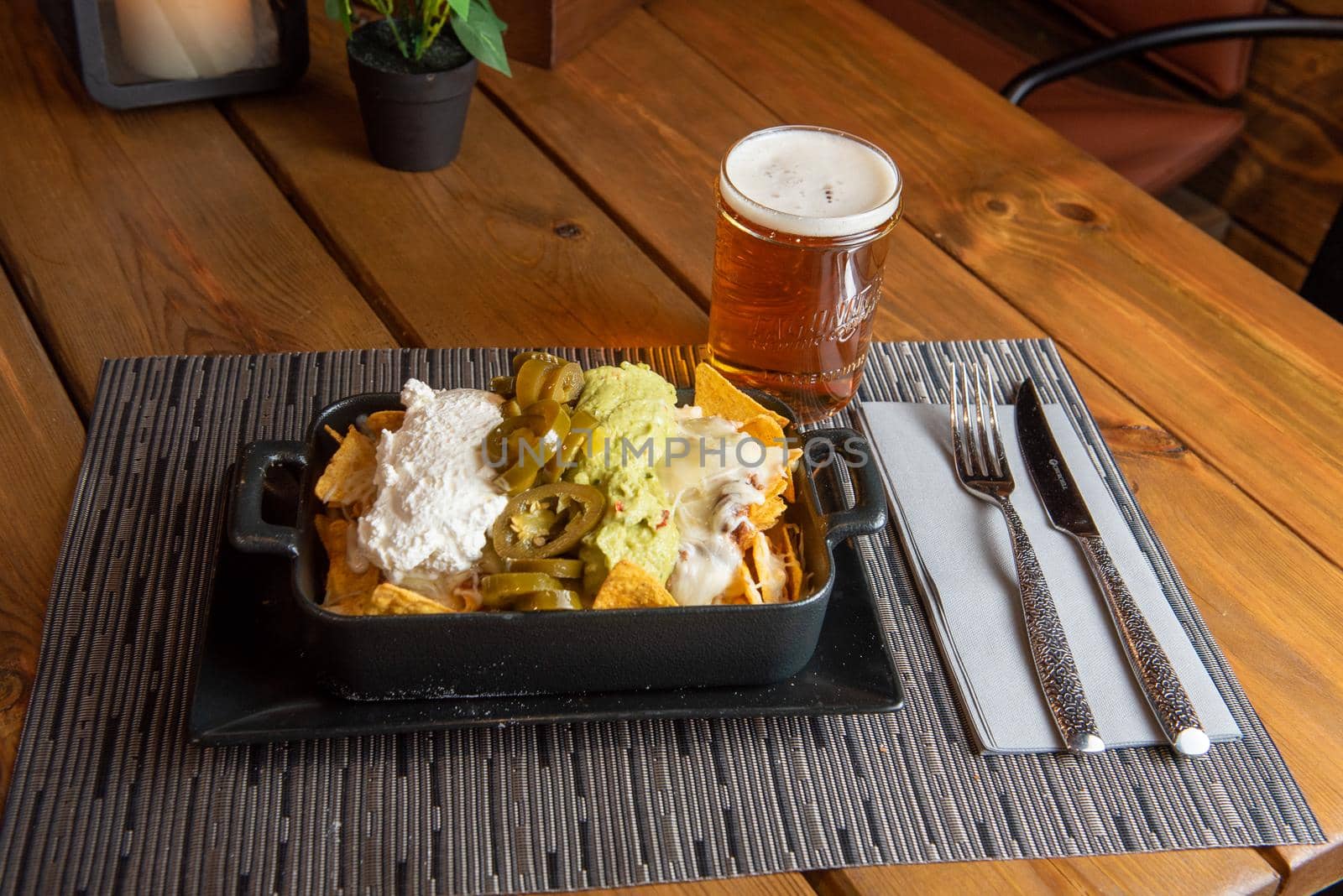 Nachos with glass of draft beer on wooden background.