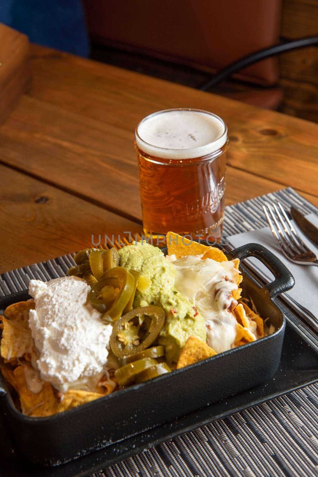 Nachos with glass of draft beer on wooden background.