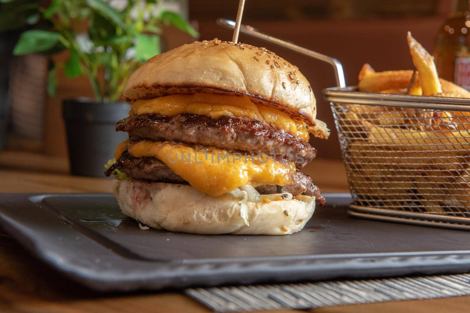 Homemade hamburger with french fries on black stone flat.