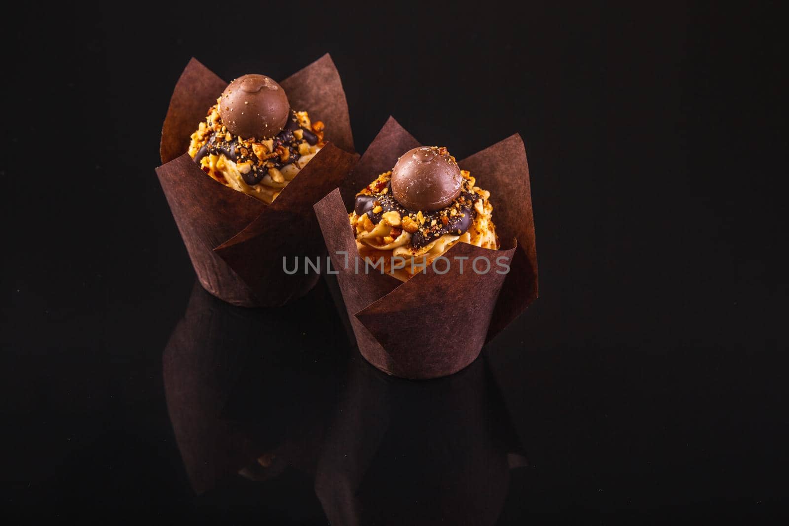 Two Peanut Butter Cupcakes On A Black Background With Reflection.