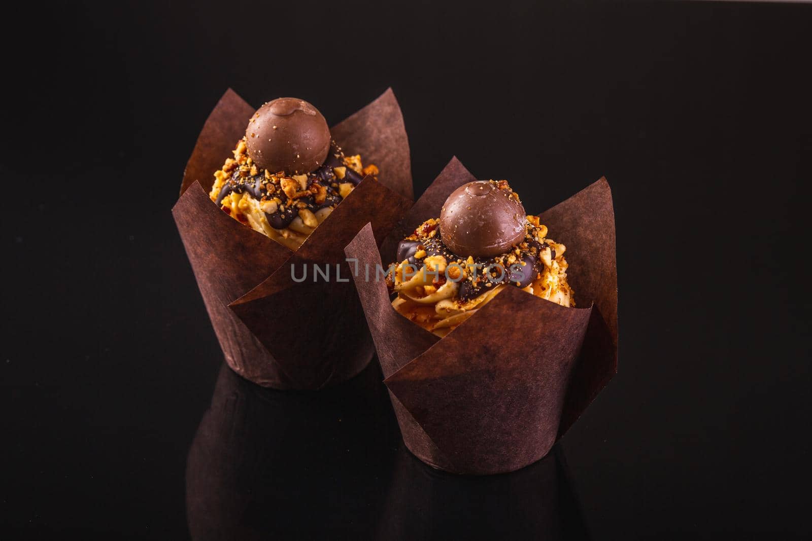 Two Peanut Butter Cupcakes On A Black Background With Reflection.