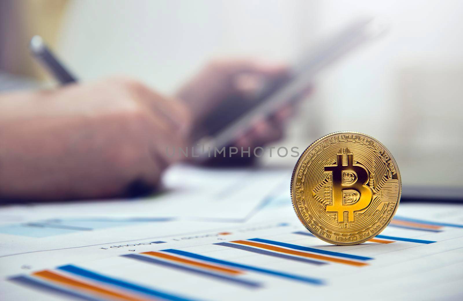 Close-up golden bitcoin on the office desk with businessman working background. by thanumporn