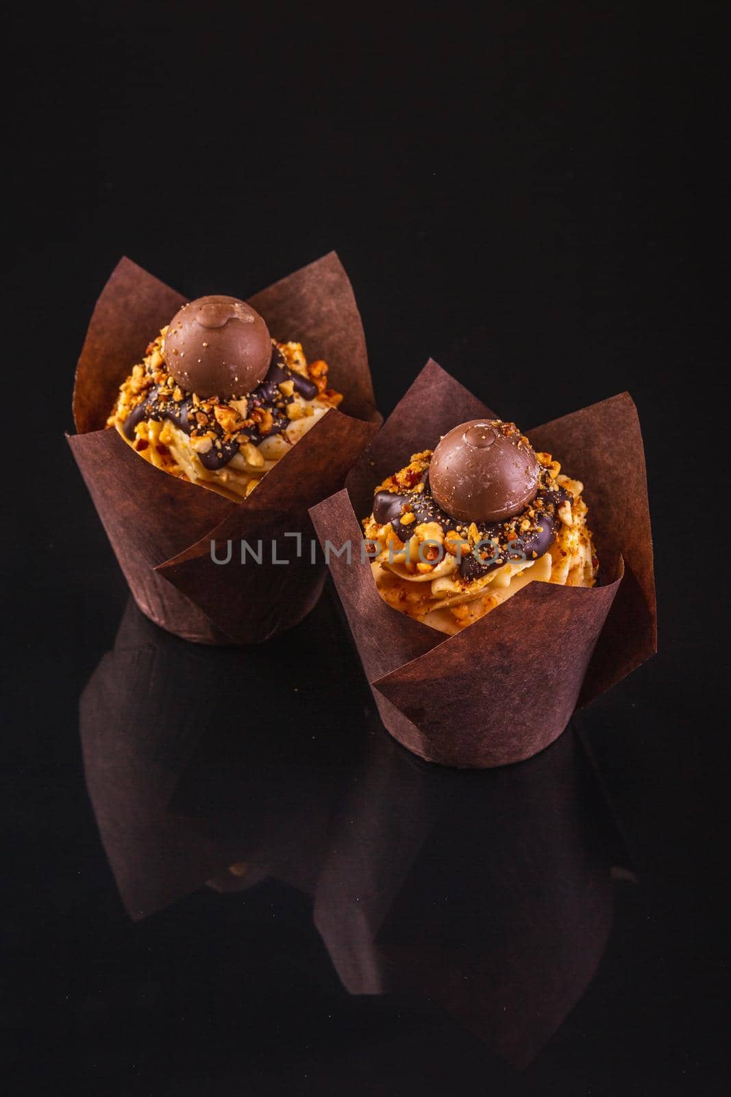 Two Peanut Butter Cupcakes On A Black Background With Reflection.